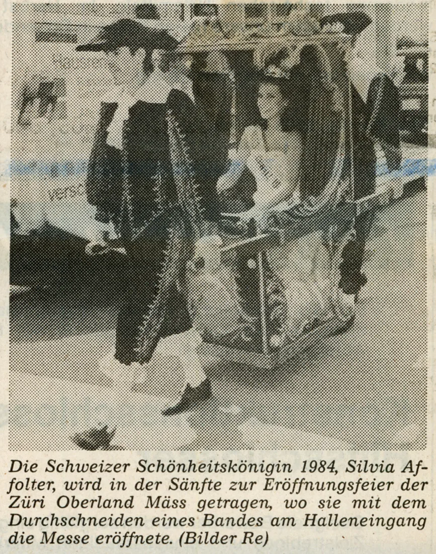 Eine Frau mit Krone auf einer Sänfte.